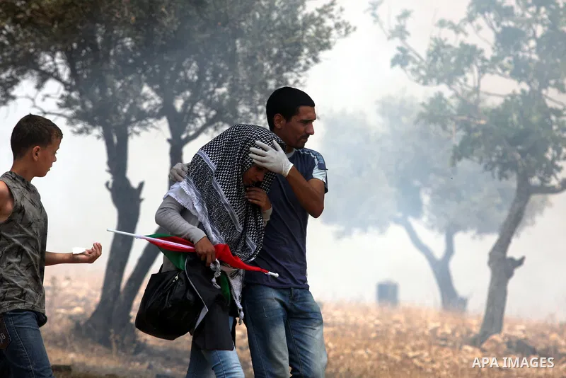 A Palestinian protester helps a wounded man during clashes with Israeli soldiers in the West Bank village of Nabi Saleh, near Ramallah, on June 22, 2012, following a demonstration against the confiscation of Palestinian...