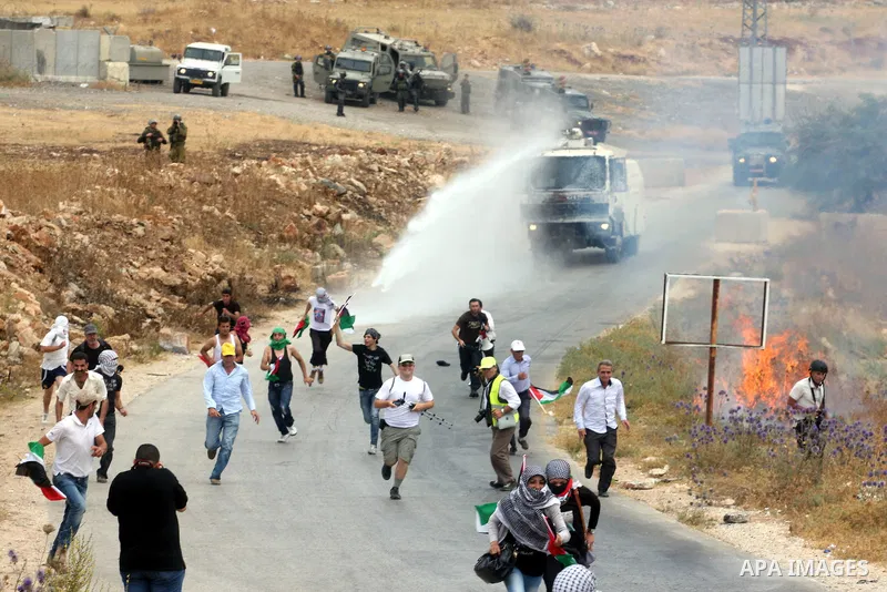 Israeli truck spray foul smelling water towards Palestinian protesters during clashes with Israeli soldiers in the West Bank village of Nabi Saleh, near Ramallah, on June 22, 2012, following a demonstration against the c...