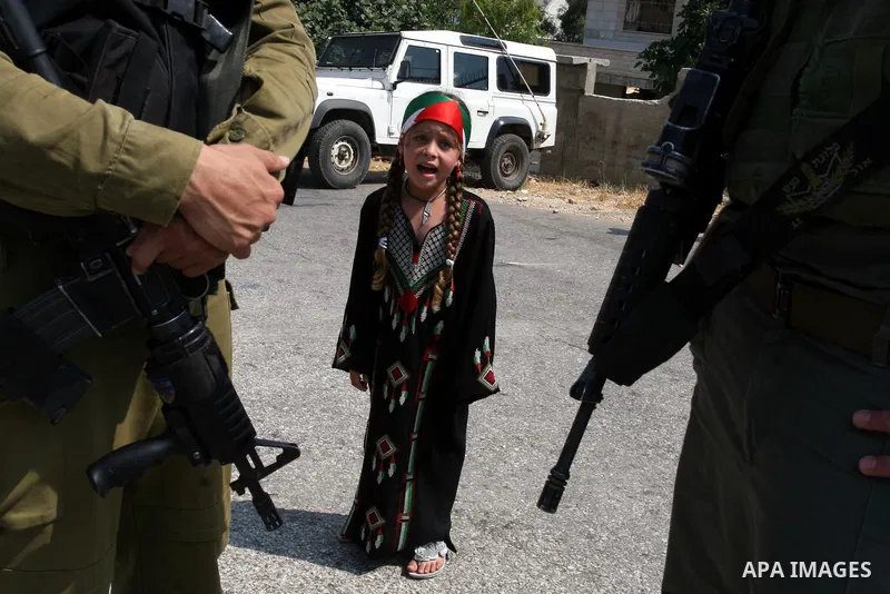 A Palestinian girl stands in front of Israeli soldiers during clashes with Palestinian protesters in the West Bank village of Nabi Saleh, near Ramallah, on June 22, 2012, following a demonstration against the confiscatio...