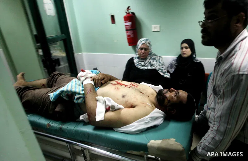 Palestinian medics wheel a wounded man to the treatment room of Al-Aqsa hospital following an Israeli airstrike east of Bureij refugee camp, in Deir Al Balah, central Gaza strip, Friday, June 22, 2012. An Israeli air str...