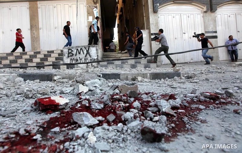 Palestinian children stand looking at the blood stained street following an Israeli strike on Gaza City on June 23, 2012. A Palestinian teenager riding a motorcycle was killed and 10 passers-by wounded in a fresh Israeli...