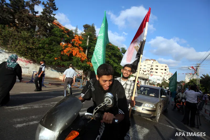 Palestinians hold national and Egyptian flags as they celebrate in Gaza City, the victory of Muslim Brotherhood's presidential candidate, Mohamed Morsi, in the Egyptian elections on June 24, 2012. Arab governments and le...