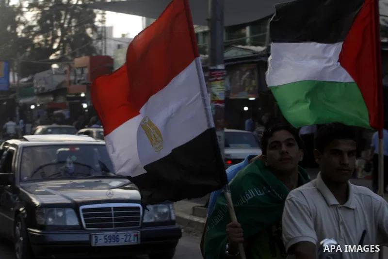 Palestinians hold national and Egyptian flags as they celebrate in Rafah town, in the southern Gaza Strip, the victory of the Muslim Brotherhood's presidential candidate, Mohamed Morsi in the Egyptian presidential electi...