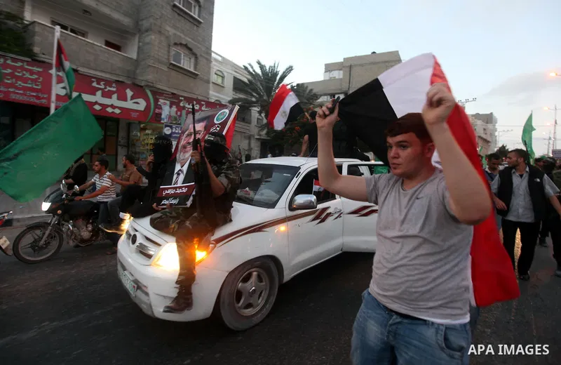 Hamas militants hold a poster depicting Mohamed Morsy of the Muslim Brotherhood as they celebrate in the street in Gaza City after he was declared Egypt's first democratic president June 24, 2012. Morsy's win was hailed...
