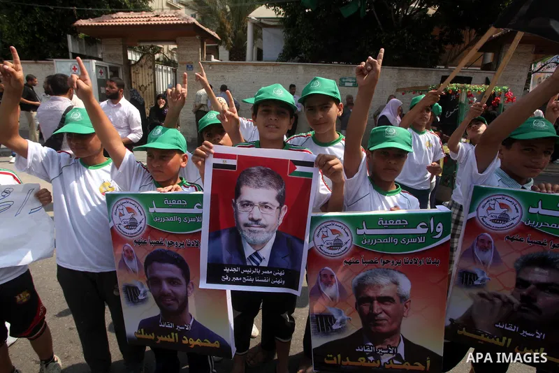 Palestinian boys supporter hold up images for Mohamed Morsi's and palestinian prisoners during celebrations after Muslim Brotherhood's presidential candidate Mohamed Morsi's victory in the Egyptian elections. Palestinian...