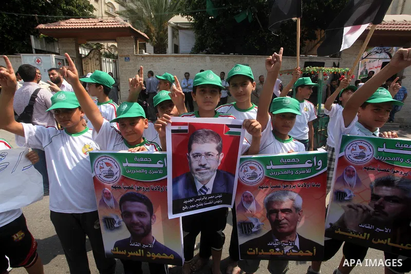 Palestinian boys supporter hold up images for Mohamed Morsi's and palestinian prisoners during celebrations after Muslim Brotherhood's presidential candidate Mohamed Morsi's victory in the Egyptian elections. Palestinian...