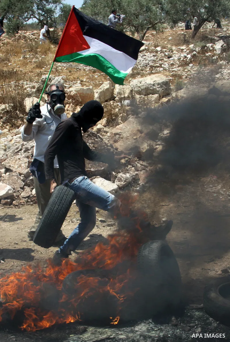 A Palestinian protestor sets a tyre on fire during clashes with Israeli troops following a weekly protest against the Jewish settlement of Kdumim, near Nablus,in the northern West Bank village of Kufr Qaddum, June 29, 20...