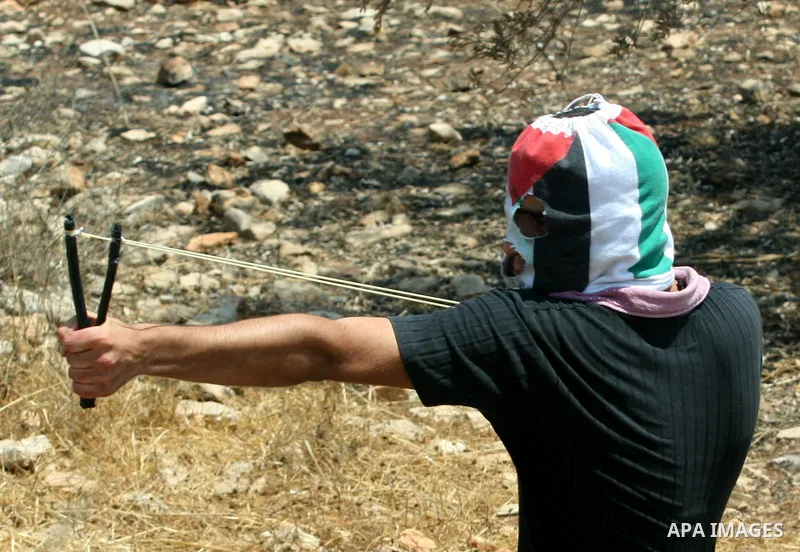 A Palestinian protestor throws stones during clashes with Israeli troops following a weekly protest against the Jewish settlement of Kdumim, near Nablus,in the northern West Bank village of Kufr Qaddum, June 29, 2012. Ph...