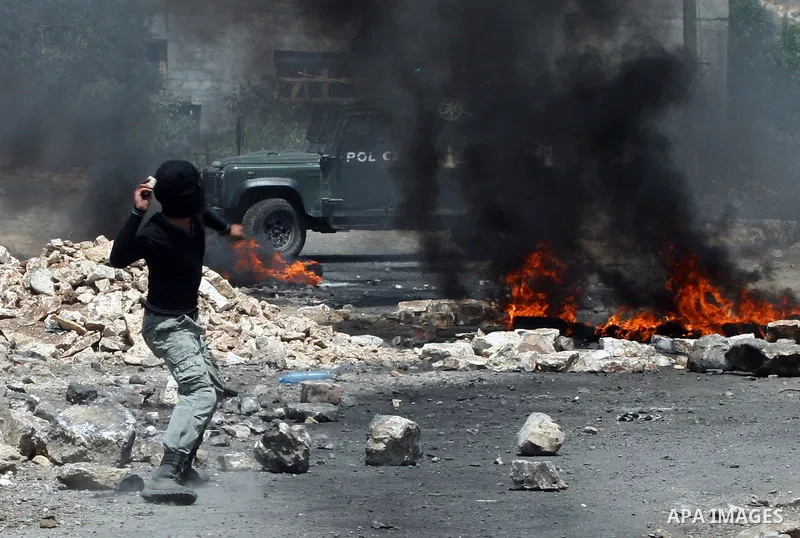 A Palestinian protestor throws stones during clashes with Israeli troops following a weekly protest against the Jewish settlement of Kdumim, near Nablus,in the northern West Bank village of Kufr Qaddum, June 29, 2012. Ph...