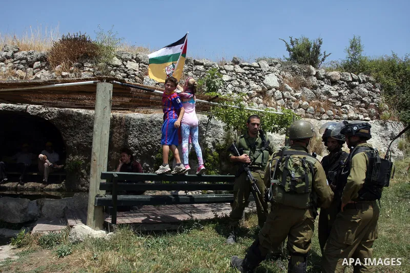 Palestinian children set a Palestinian flag during a demonstration against Israel's separation barrier in the West Bank village of Nabi Saleh near Ramallah, , Friday, June 29, 2012. Palestinians protest weekly against th...