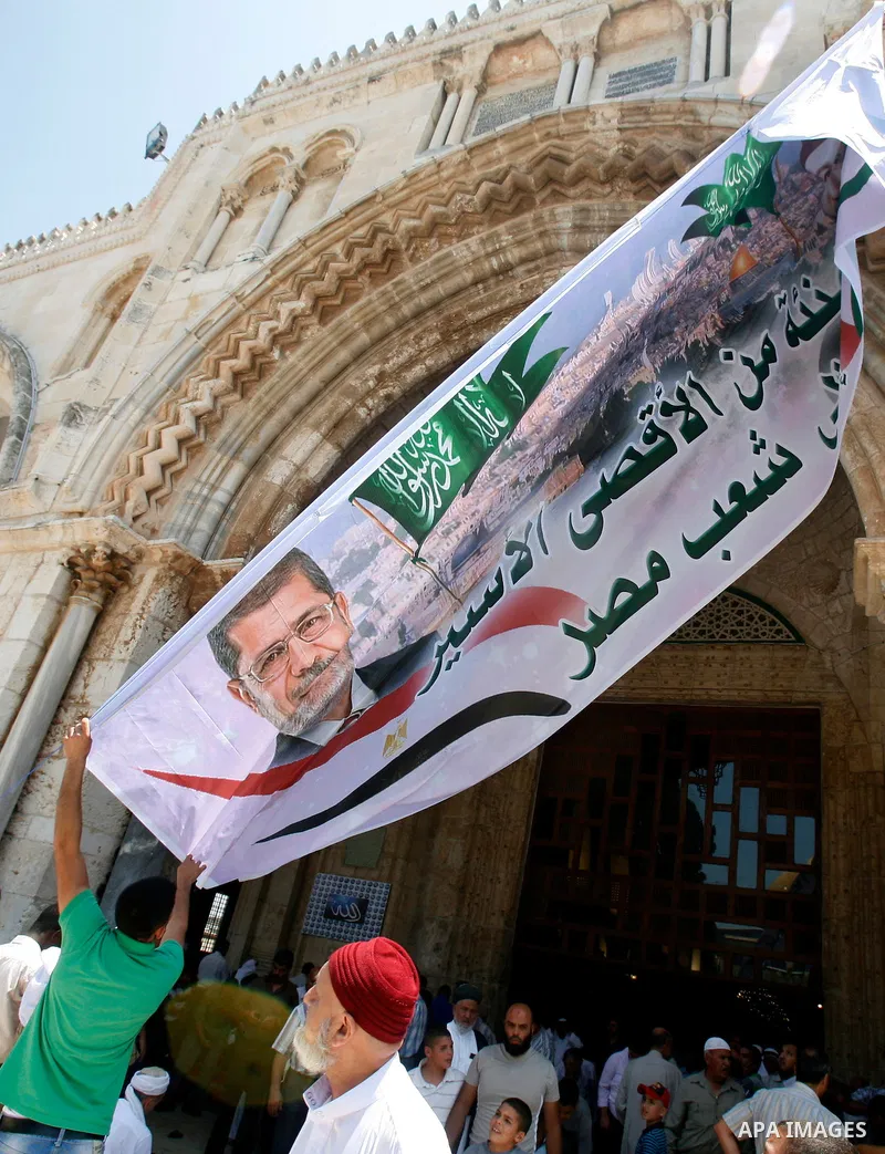 Palestinians hold up a banner with pictures for Egyptian President-elect Mohammed Morsi and Sheikh Hasan al-Bana founder of Muslim Brotherhood, in front of al-Aqsa Mosque on 29 June 2012, during a rally in the old city o...