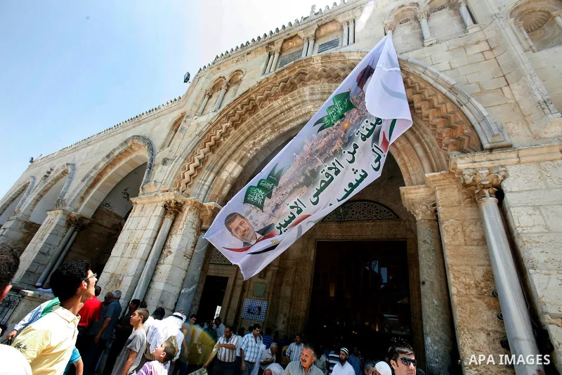 Palestinians hold up a banner with pictures for Egyptian President-elect Mohammed Morsi and Sheikh Hasan al-Bana founder of Muslim Brotherhood, in front of al-Aqsa Mosque on 29 June 2012, during a rally in the old city o...