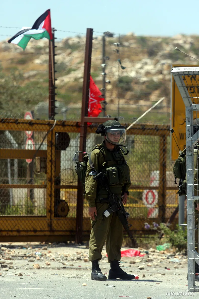 An Israeli soldier takes cover during clashes with Palestinian protestors following a demonstration outside Ofer prison, near the West Bank city of Ramallah,on Sunday, July, 1, 2012. Photo by Issam Rimawi