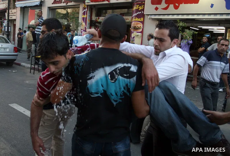 Palestinians help a wounded man, injured in a protest against a scheduled meeting between Palestinian President Mahmoud Abbas and the Israeli Vice Prime Minister Shaul Mofaz in the West Bank city of Ramallah, on 01 July...