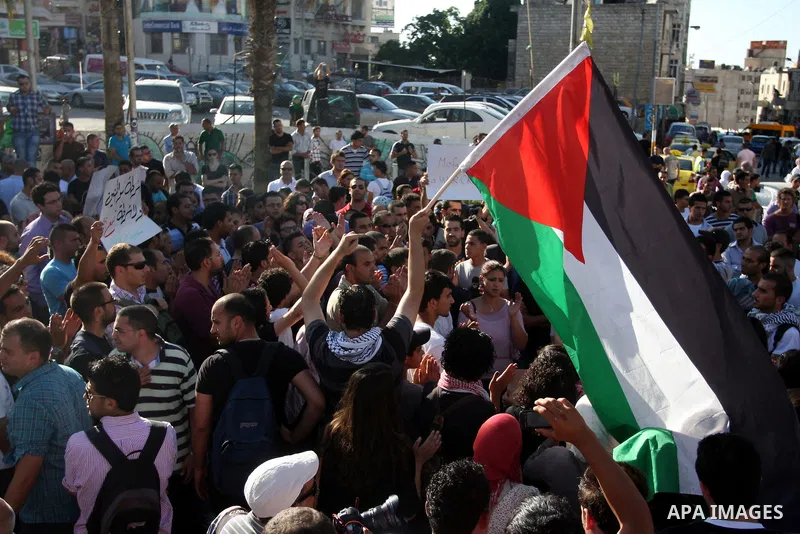 Palestinian protestors hold banners and national flags during a protest against a scheduled meeting between Palestinian President Mahmoud Abbas and the Israeli Vice Prime Minister Shaul Mofaz in the West Bank city of Ram...