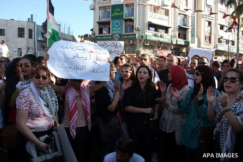 Palestinian protestors hold banners and national flags during a protest against a scheduled meeting between Palestinian President Mahmoud Abbas and the Israeli Vice Prime Minister Shaul Mofaz in the West Bank city of Ram...