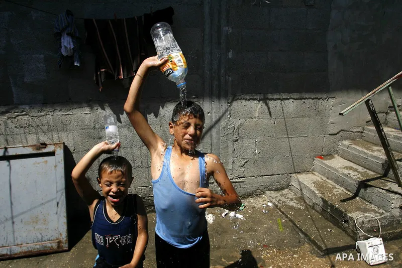 Palestinian children enjoy themselves with water during hot weather and high temperature in the southern Gaza Strip town of Rafah on July 02, 2012. Photo by Eyad Al Baba