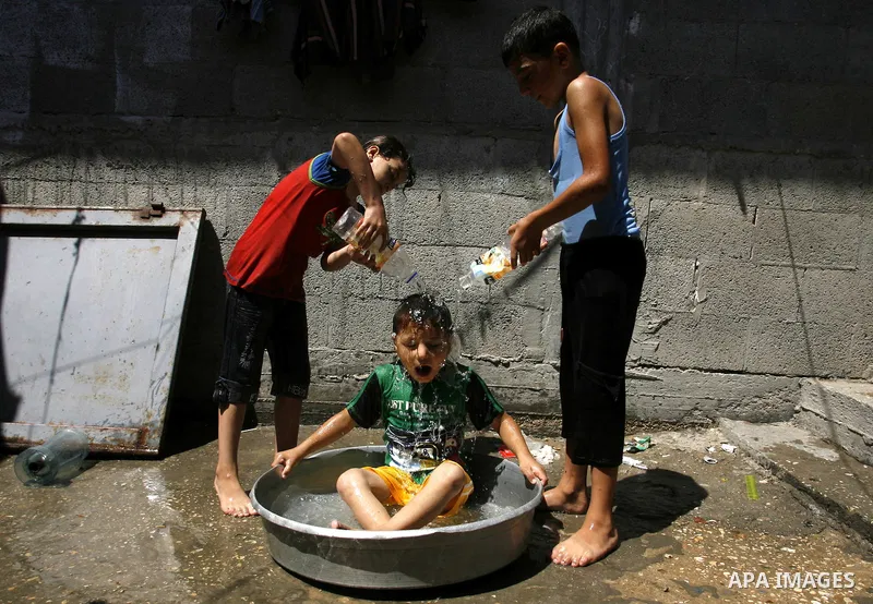 Palestinian children enjoy themselves with water during hot weather and high temperature in the southern Gaza Strip town of Rafah on July 02, 2012. Photo by Eyad Al Baba