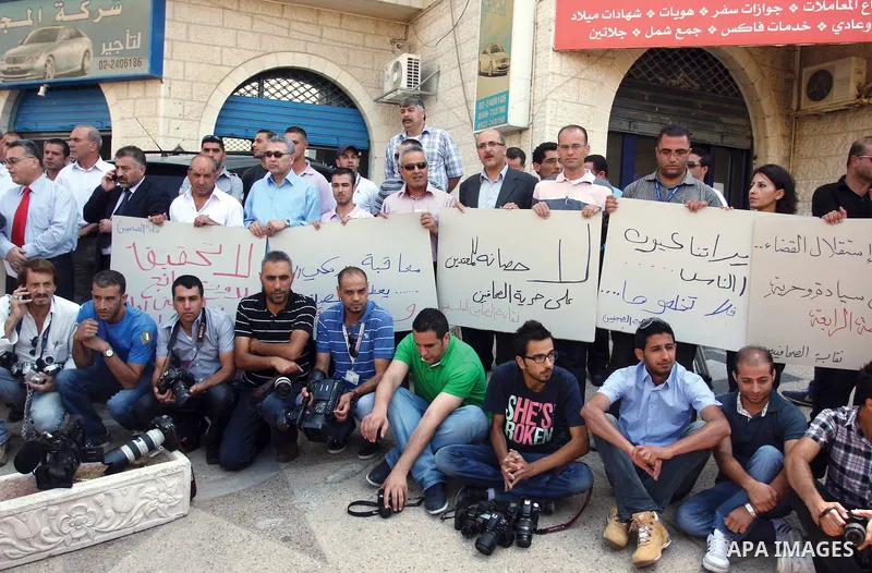 Palestinian Photojournalists hold banners and cameras outside the office of the Palestinian Interior Ministry in the West Bank city of Ramallah, July 03, 2012. Journalists protested against the assault by Palestinian pol...