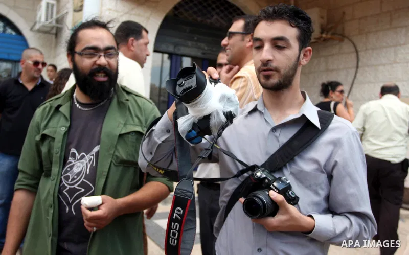Palestinian Photojournalists hold banners and cameras outside the office of the Palestinian Interior Ministry in the West Bank city of Ramallah, July 03, 2012. Journalists protested against the assault by Palestinian pol...