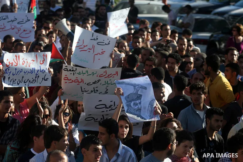 Palestinian demonstrators hold a national flag in the West Bank city of Ramallah on July 3, 2012 to protest against the violent dispersal of two similar rallies over the weekend. The demonstration was called by the "Pale...