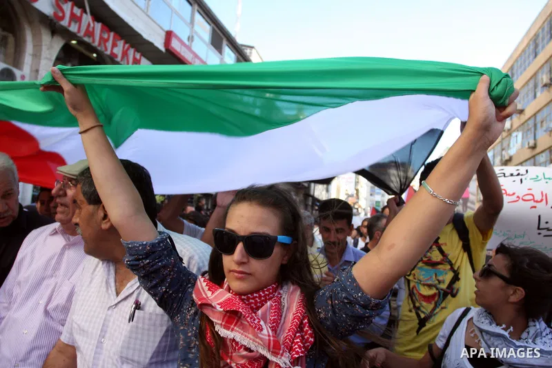 Palestinian demonstrators hold a national flag in the West Bank city of Ramallah on July 3, 2012 to protest against the violent dispersal of two similar rallies over the weekend. The demonstration was called by the "Pale...
