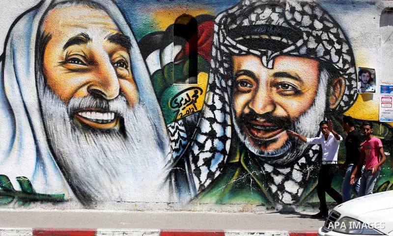 Palestinian youths walk past a mural depicting late Hamas spiritual leader Sheikh Ahmed Yassin (L) and late Palestinian leader Yasser Arafat (R) in Gaza City on July 4, 2012. Arafat, who died in 2004, was poisoned by pol...