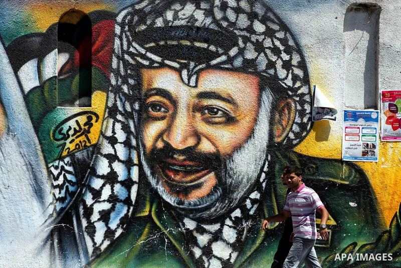 Palestinian youths walk past a mural depicting late Hamas spiritual leader Sheikh Ahmed Yassin (L) and late Palestinian leader Yasser Arafat (R) in Gaza City on July 4, 2012. Arafat, who died in 2004, was poisoned by pol...