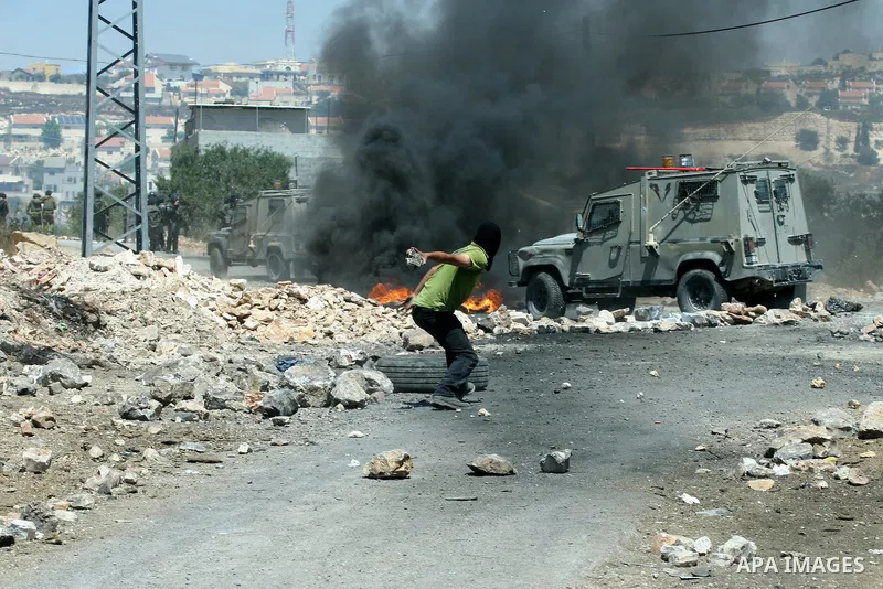 A Palestinian demonstrator throws stones towards Israeli border police during a protest against the expansion of the nearby Jewish settlement of Kdumim, in the northern West Bank village of Kufr Qaddum, on 06 July 2012....