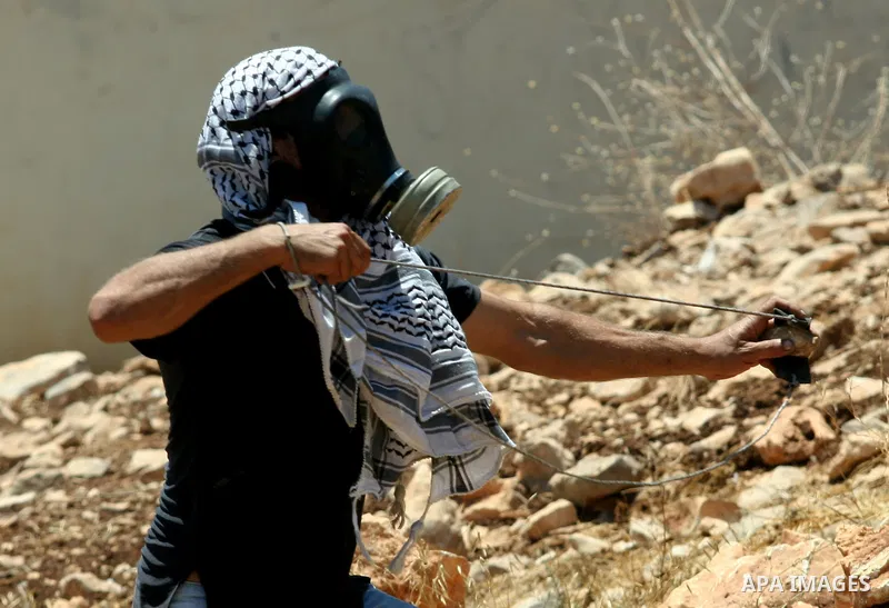 A Palestinian demonstrator throws stones towards Israeli border police during a protest against the expansion of the nearby Jewish settlement of Kdumim, in the northern West Bank village of Kufr Qaddum, on 06 July 2012....