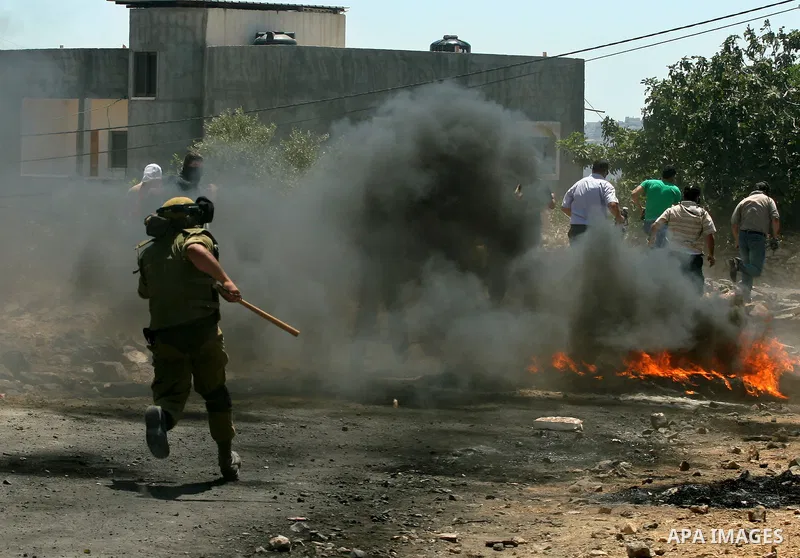 Palestinians run away cover from teargas during clashes with Israeli border policemen following a protest against the expansion of the nearby Jewish settlement of Kdumim, in the northern West Bank village of Kufr Qaddum,...