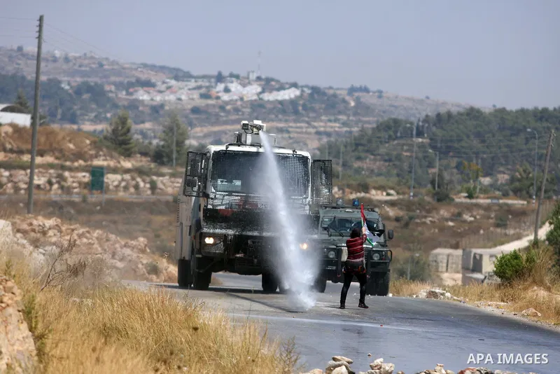 A Palestinian woman waves a Palestinian flag in front of a truck spraying foul smelling water during clashes with Israeli soldiers at a weekly protest against a nearby Jewish settlement, in the West Bank village of Nabi...