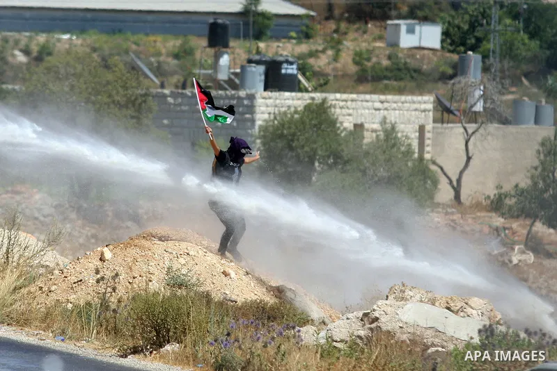 A Palestinian woman waves a Palestinian flag in front of a truck spraying foul smelling water during clashes with Israeli soldiers at a weekly protest against a nearby Jewish settlement, in the West Bank village of Nabi...