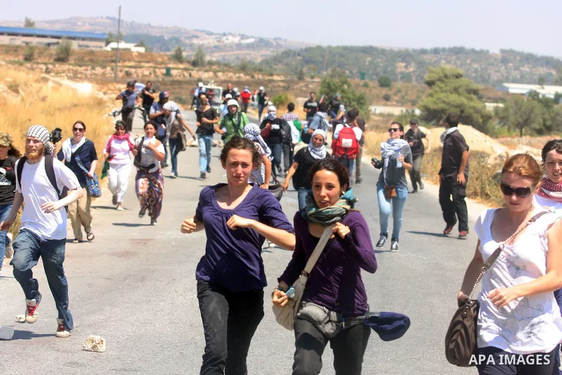 Palestinian and foreign activists run away during clashes with Israeli soldiers following a weekly protest against a nearby Jewish settlement, in the West Bank village of Nabi Saleh, near Ramallah July 6, 2012. Photo by...