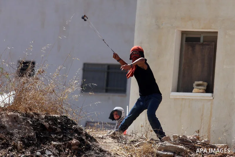 A Palestinian protester fires a stone from a slingshot towards Israeli soldiers during clashes at a weekly protest against a nearby Jewish settlement, in the West Bank village of Nabi Saleh, near Ramallah July 6, 2012. P...
