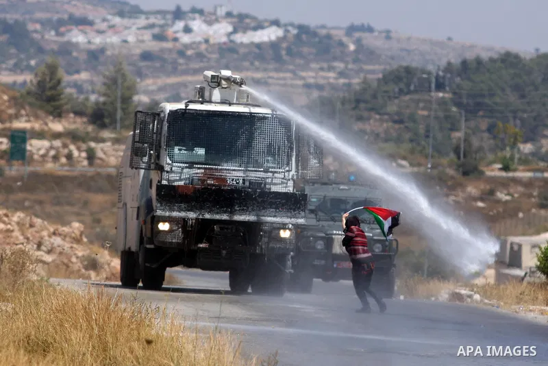 A Palestinian woman waves a Palestinian flag in front of a truck spraying foul smelling water during clashes with Israeli soldiers at a weekly protest against a nearby Jewish settlement, in the West Bank village of Nabi...