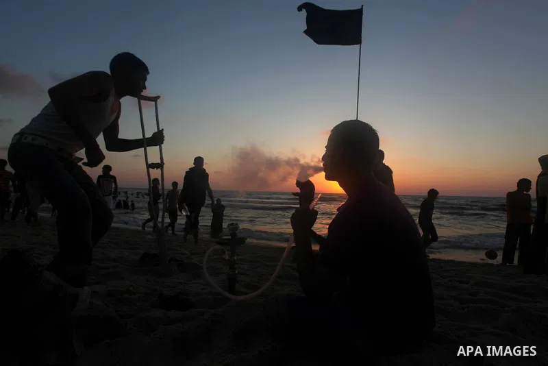 Palestinian youths smoke the water pipes on the beach on their week-end in the Mediterranean sea in Gaza City on July 06, 2012. Photo by Ashraf Amra