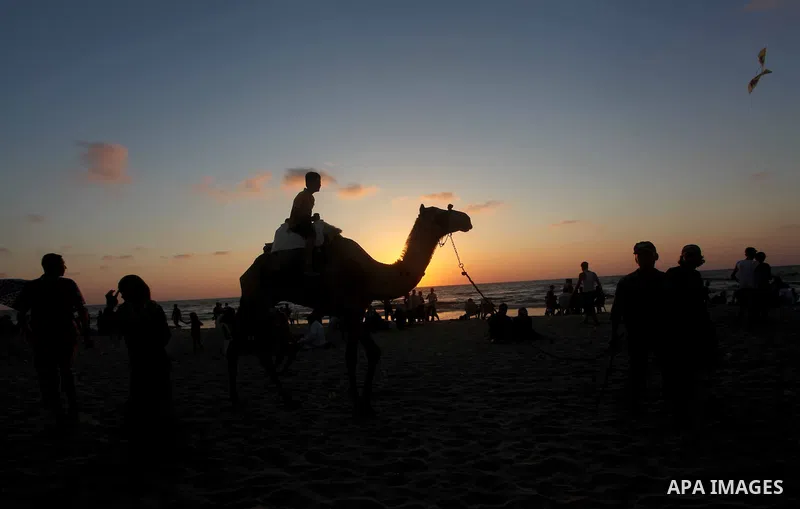 A Palestinian man rides a camel on the beach on their week-end in the Mediterranean port of Gaza on July 06, 2012. Photo by Ashraf Amra