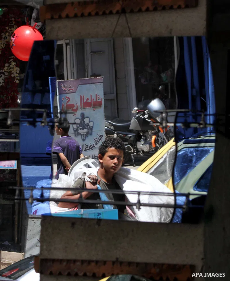 Palestinians are reflected in mirrors for sale as they walk through a traditional market in the refugee camp of Jabaliya, in the northern Gaza Strip, 07 July 2012 . Photo by Ashraf Amra