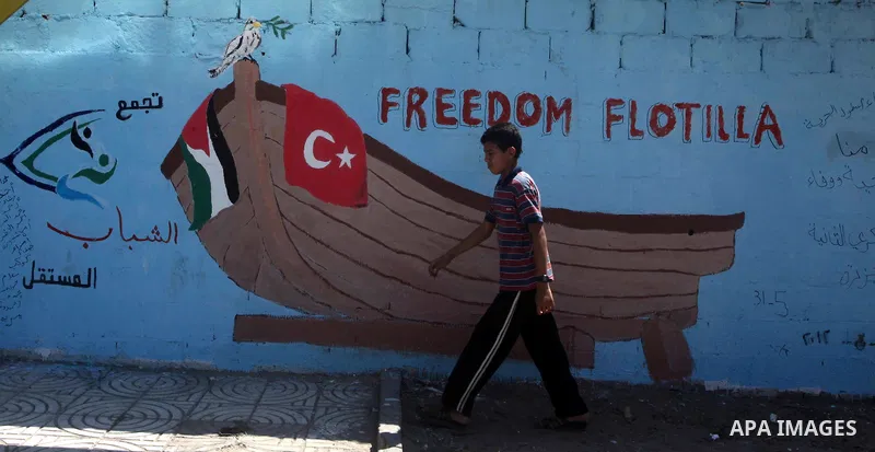 Palestinian boy walks past a mural depicting Turkish ship of Marmara the Israeli commando of raid on a flotilla attempting to break the blockade on Gaza July 7, 2012.. Photo by Ashraf Amra