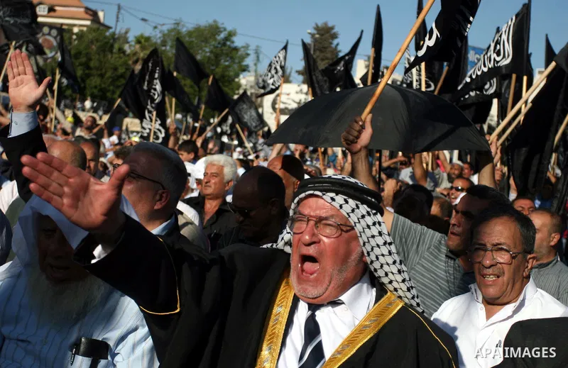 Palestinian supporters of Hizb ut-Tahrir or the Islamic Liberation Party, chant slogans and wave black and white flags with the religous writing "There is no God but God, and Mohammed is his prophet" during a rally in th...