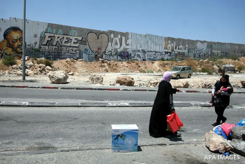 Palestinian women walk past the wall of separation between Ramallah and Jerusalem, July 9, 2012. Eight years ago, specifically in 2004, has taken International Court of Justice, judicial arm statute of the United Nations...