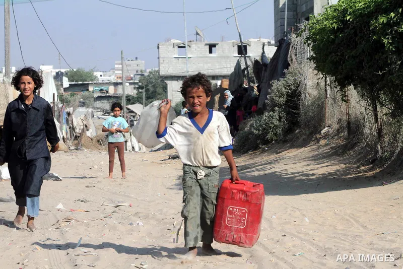 Palestinian children carry water bottles in Zeitoun neighborhood southern Gaza city on 09 July 2012. Photo by Ashraf Amra