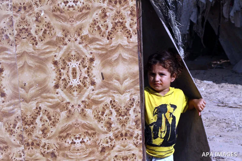 A Palestinian child looks through a mat of straw in front her home in Zeitoun neighborhood southern Gaza city on 09 July 2012. Photo by Ashraf Amra
