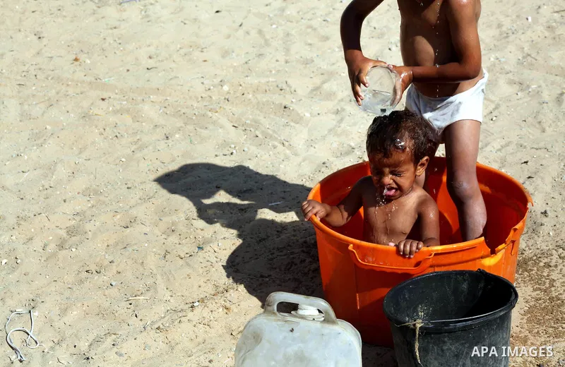 A Palestinian child bathes his brother in front of their home in Zeitoun neighborhood southern Gaza city on 09 July 2012. Photo by Ashraf Amra