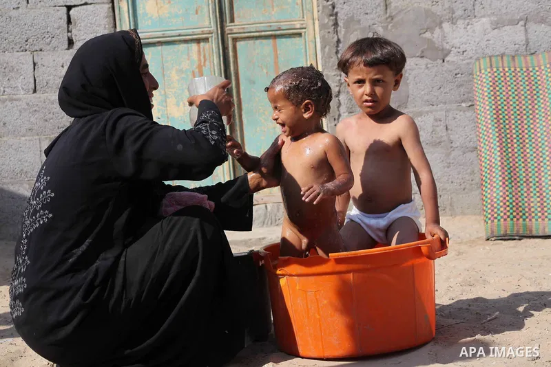 A Palestinian woman bathes her children in front of her home in Zeitoun neighborhood southern Gaza city on 09 July 2012. Photo by Ashraf Amra