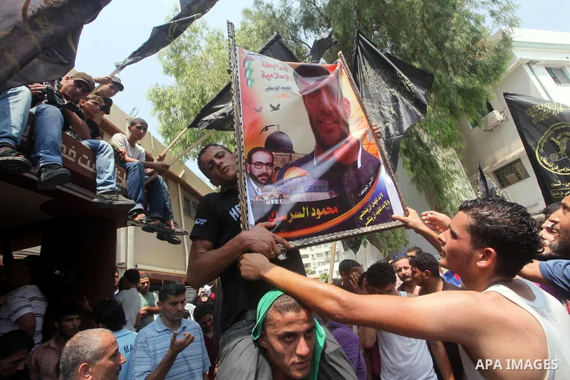 Palestinians hold pictures of Palestinian soccer player Mahmoud Al-Sarsak upon his arrival in Gaza City July 10, 2012. Israel released the Gaza soccer player on Tuesday in a deal to end his intermittent four-month hunger...
