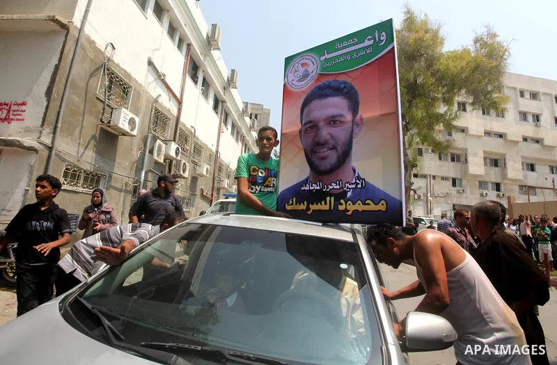 Palestinians hold pictures of Palestinian soccer player Mahmoud Al-Sarsak upon his arrival in Gaza City July 10, 2012. Israel released the Gaza soccer player on Tuesday in a deal to end his intermittent four-month hunger...