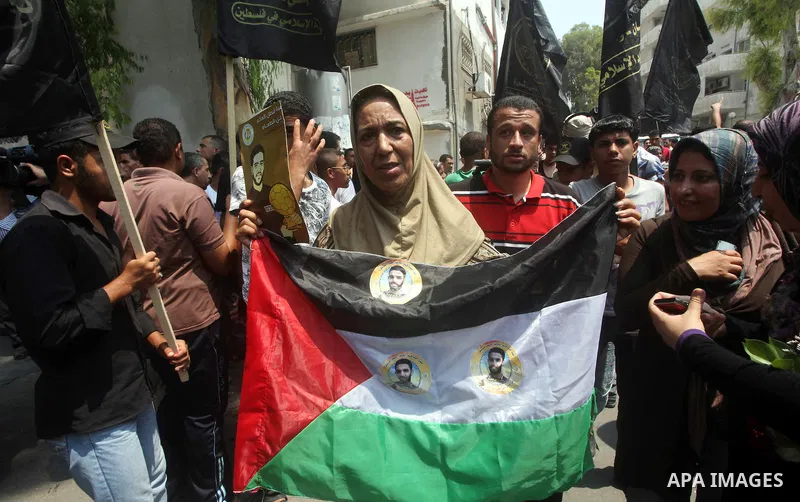 Palestinians hold pictures of Palestinian soccer player Mahmoud Al-Sarsak upon his arrival in Gaza City July 10, 2012. Israel released the Gaza soccer player on Tuesday in a deal to end his intermittent four-month hunger...