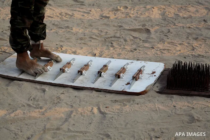 A Palestinian trainer walks on sharp knifes during training in a summer camp organized by Hamas movement at Shati refugee camp in Gaza City July 10, 2012. Hamas movement organized dozens of summer camps for Palestinian c...